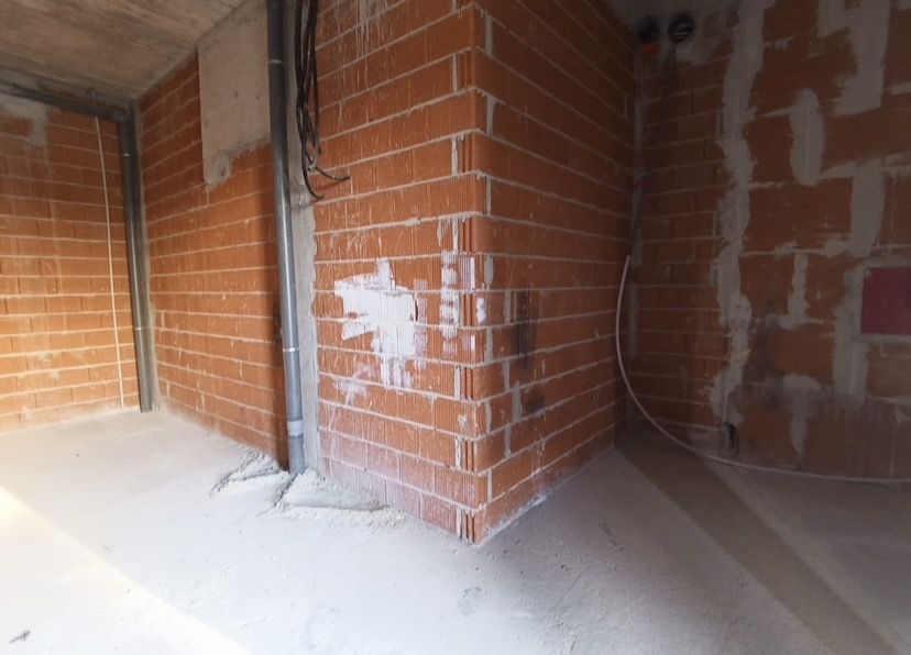 Esquina de fábrica de ladrillo enfoscada parcialmente